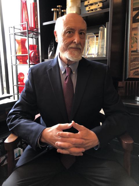 David Johnson seated in a suit in a room with shelves