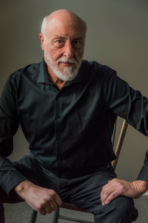 David Johnson seated in a black shirt against a warm gray background